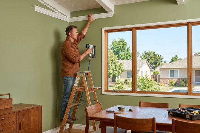 Carpenter installing white crown molding with crisp corner joints in a Placentia dining room